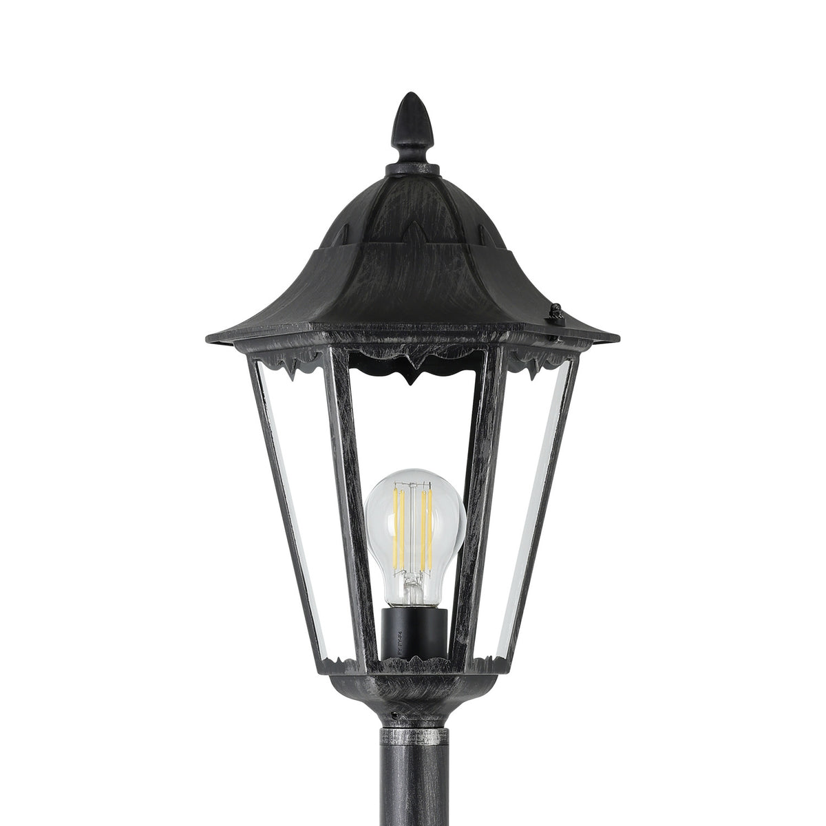 Nolmane outdoor floor lamp with a hexagonal glass-paned lantern head, curved canopy, pointed finial and visible E27 bulb, in black aluminium with silver patina, shown on a plain white background.