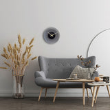 Float Round Silent Frosted Glass Wall Clock, 40cm, with black centre dial and gold hands, shown above a grey sofa in a living room setting.