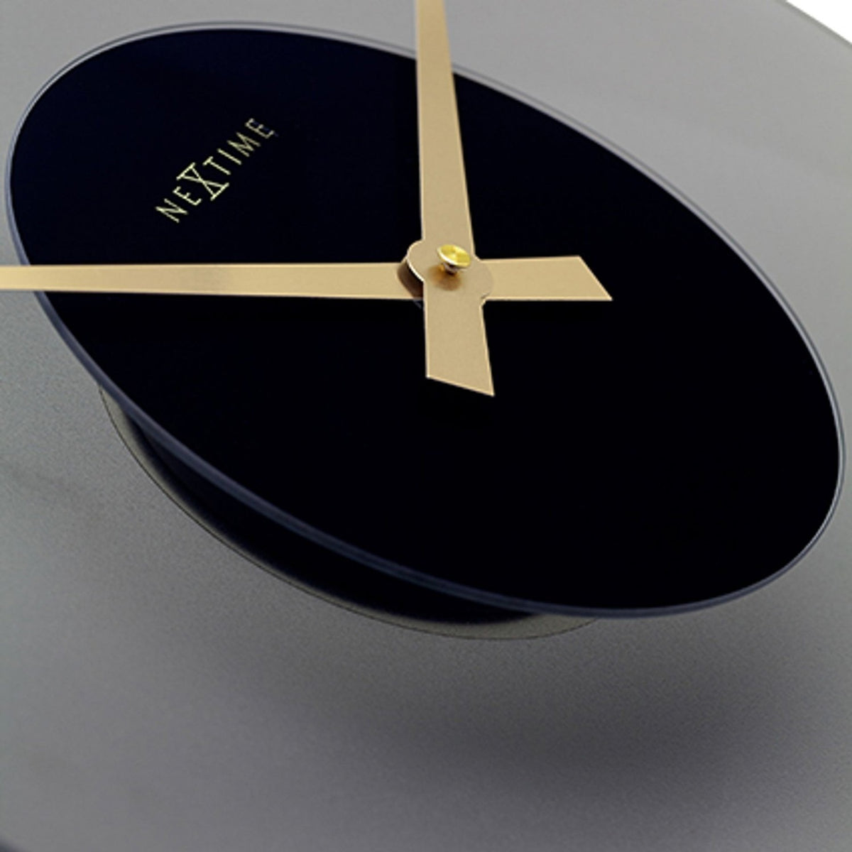 Close-up of the Float Round Silent Wall Clock 40cm, showing a black glass dial with gold hands and "NeXtime" logo, set against a curved frosted grey glass edge.