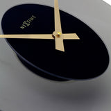 Close-up of the Float Round Silent Wall Clock 40cm, showing a black glass dial with gold hands and "NeXtime" logo, set against a curved frosted grey glass edge.