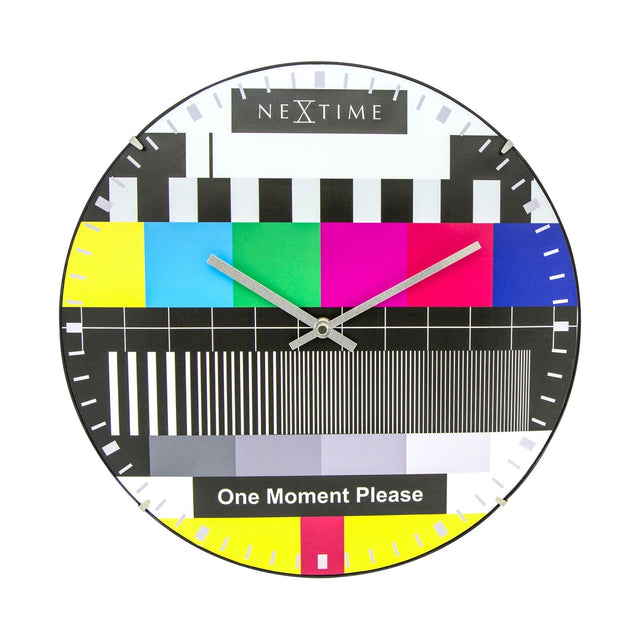 Round wall clock with domed glass face showing a TV test card design: colour bars, black and white stripes, grey tones, and silver hands, on a plain white background.