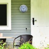 Poppy Galvanised Colour Deep Round Wall Clock 22cm in silver with white dial and black hands, mounted on grey porch siding beside a door, wicker chair below.