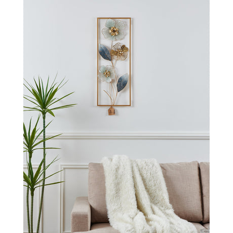 Numazu Wall Decoration, a tall gold-framed metal wall art with pale blue and gold flowers on curving stems with blue-grey leaves, shown above a sofa in a living room.