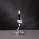 The Nydia 1 Light Crystal Table Lamp features a polished chrome base, curved stem, star-shaped crystal accent, and dimmable lighting that glows beautifully against a dark background.
