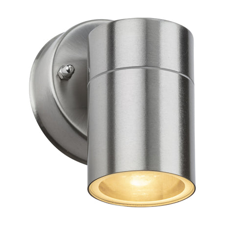 OBEX cylindrical outdoor wall light in brushed chrome stainless steel with a round wall plate, mounting screw, and clear glass lens lit from within, on a plain white background.