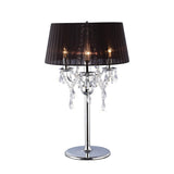 The Olivia 3 Light Crystal Table Lamp features a polished chrome finish, black shade, ornate arms, hanging crystal accents, and pleated design for a warm, inviting glow.