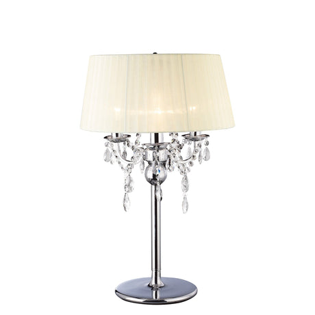 The Olivia 3 Light Crystal Table Lamp features a polished chrome base, hanging crystal accents, and an ivory cream shade, displayed on a plain white background.