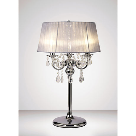 The Olivia 3 Light Crystal Table Lamp features a polished chrome base, grey shade, and hanging crystal accents, providing soft ambient lighting and a warm glow.