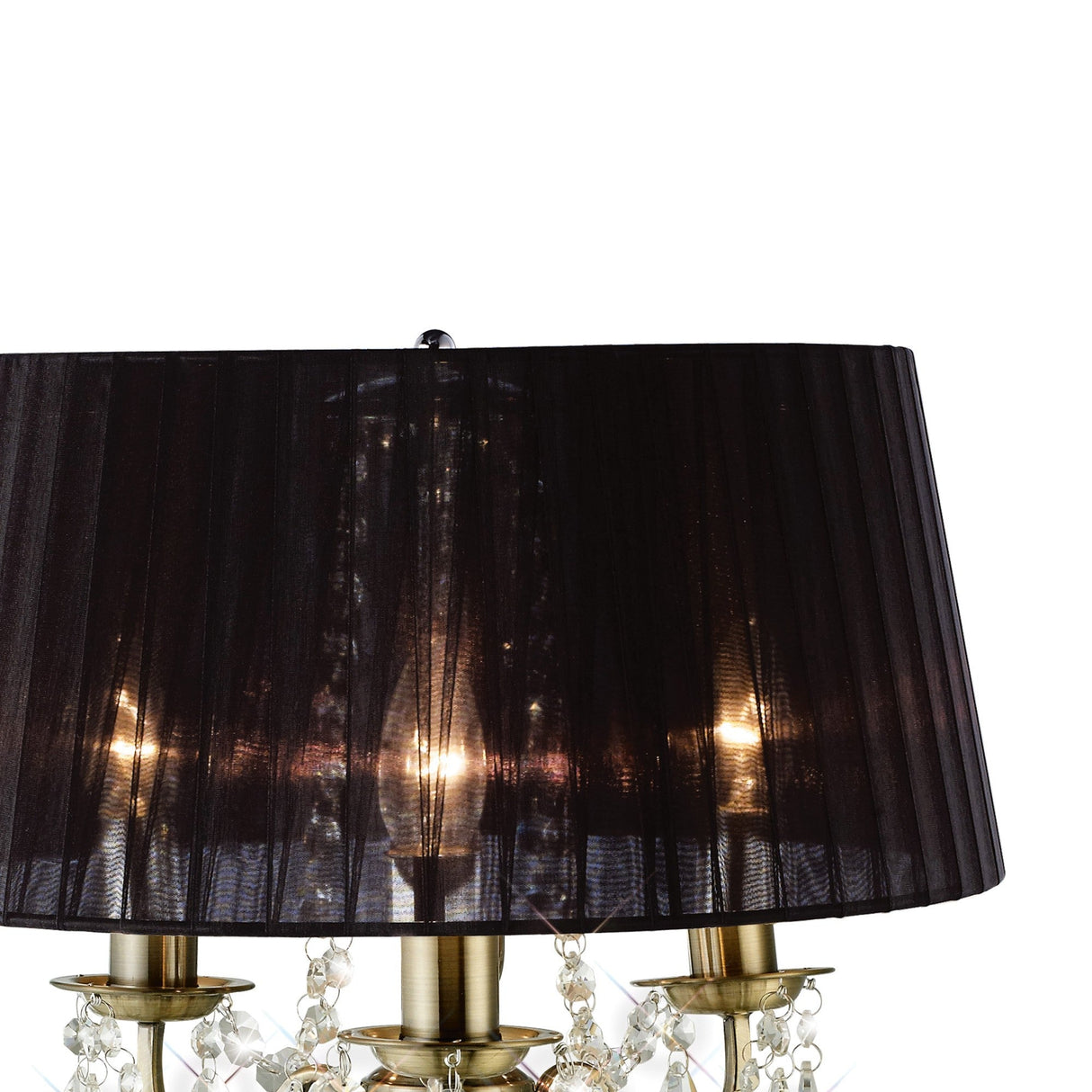 The Olivia 3 Light Crystal Table Lamp features an antique brass base, candle-style lights, and a large black pleated shade. Crystal accents hang below the shade, enhancing its elegance against a white background.