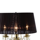 The Olivia 3 Light Crystal Table Lamp features an antique brass base, candle-style lights, and a large black pleated shade. Crystal accents hang below the shade, enhancing its elegance against a white background.