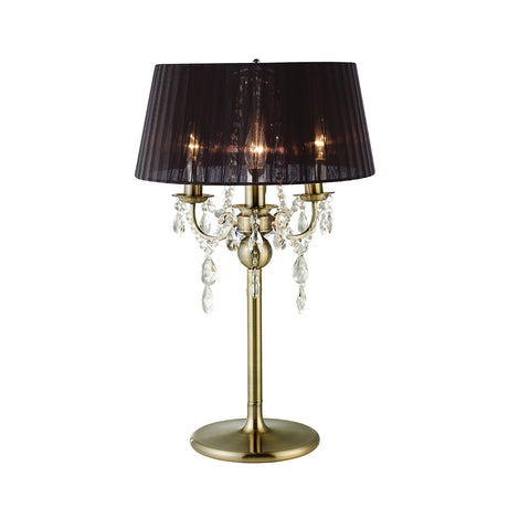 The Olivia 3 Light Crystal Table Lamp features an antique brass finish, black pleated shade, crystal pendants, and three candle-like bulbs on multiple arms for an elegant, classic look.