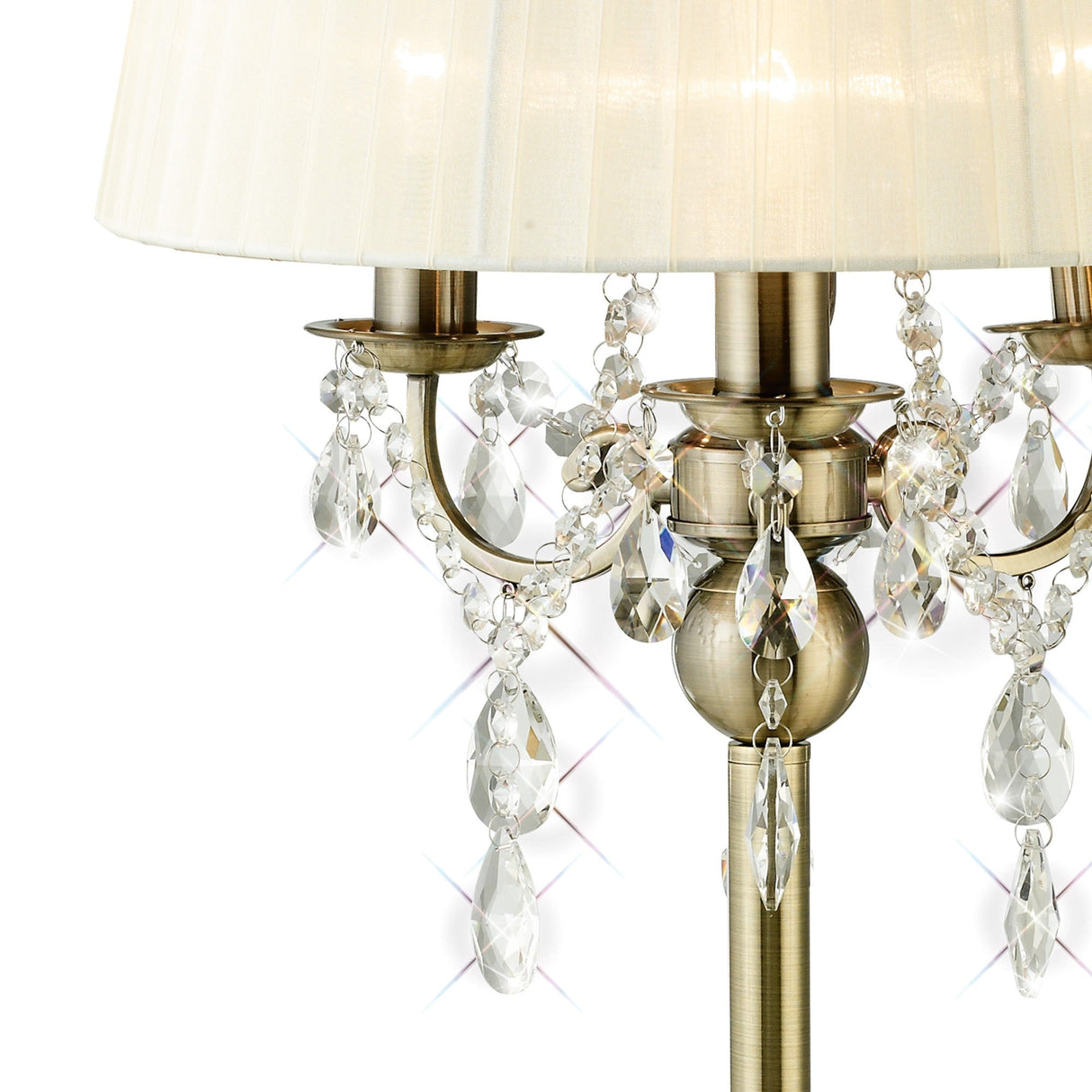 Close-up of the Olivia 3 Light Crystal Table Lamp in antique brass, with a cream fabric shade and hanging crystals that reflect light and create sparkling effects.