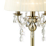 Close-up of the Olivia 3 Light Crystal Table Lamp in antique brass, with a cream fabric shade and hanging crystals that reflect light and create sparkling effects.