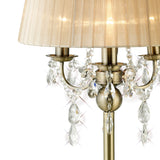 The Olivia 3 Light Crystal Table Lamp features antique brass arms, sparkling hanging crystals, and a bronze shade, reflecting light for an elegant, timeless look.