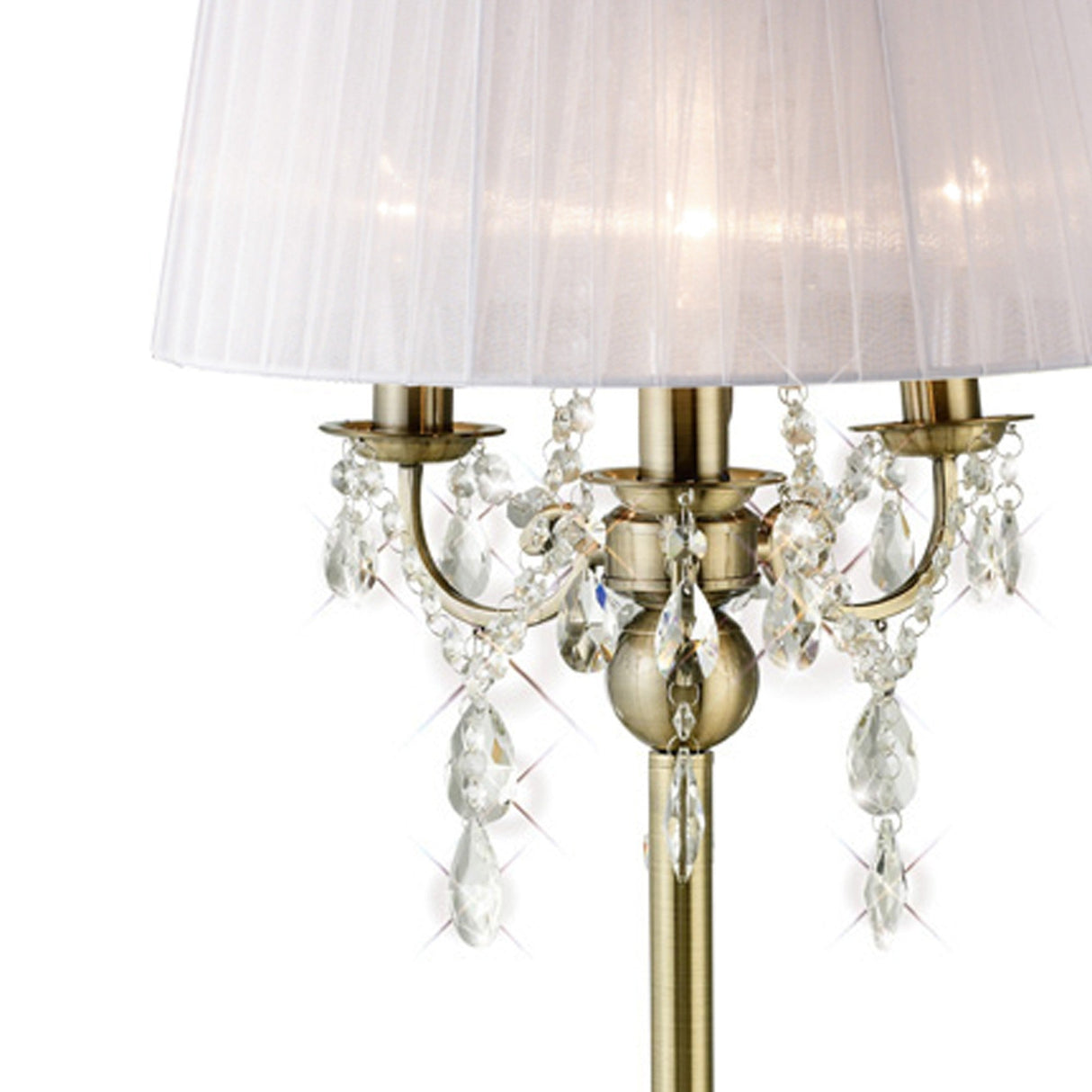 The Olivia 3 Light Crystal Table Lamp features an antique brass base, clear crystal accents, and a white shade. Clusters of crystal drops hang beneath the shade, creating an elegant lighting effect for your interior.
