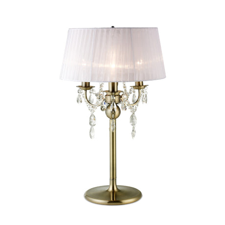 The Olivia 3 Light Crystal Table Lamp features antique brass, a white pleated shade, three candle-style bulbs, and hanging crystal accents—an elegant lighting solution for any room.
