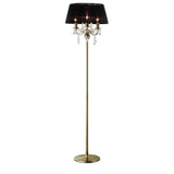 The Olivia 3 Light Crystal Floor Lamp features a tall, modern design with a brass finish, black pleated shade, round base, and three candle-style bulbs adorned with hanging crystal ornaments.