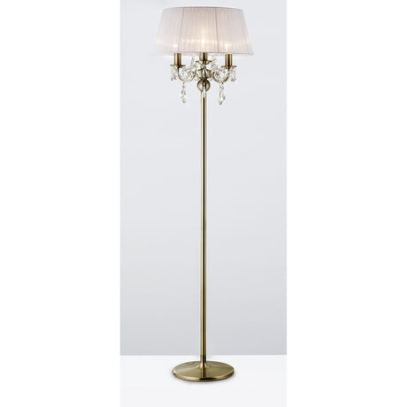 The Olivia 3 Light Crystal Floor Lamp features an antique brass finish, a round base, white pleated shade, and crystal accents hanging below the shade.