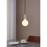 Opal Dimmable LED Globe Bulb E27 G125 glowing warm white in a white pendant fitting above a marble dining table set with a teacup and newspaper.