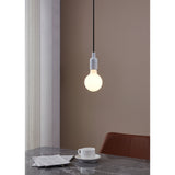 Opal Dimmable LED Globe Bulb E27 G95 glowing warm white in a white pendant fitting above a dining table, set against a soft brown wall.
