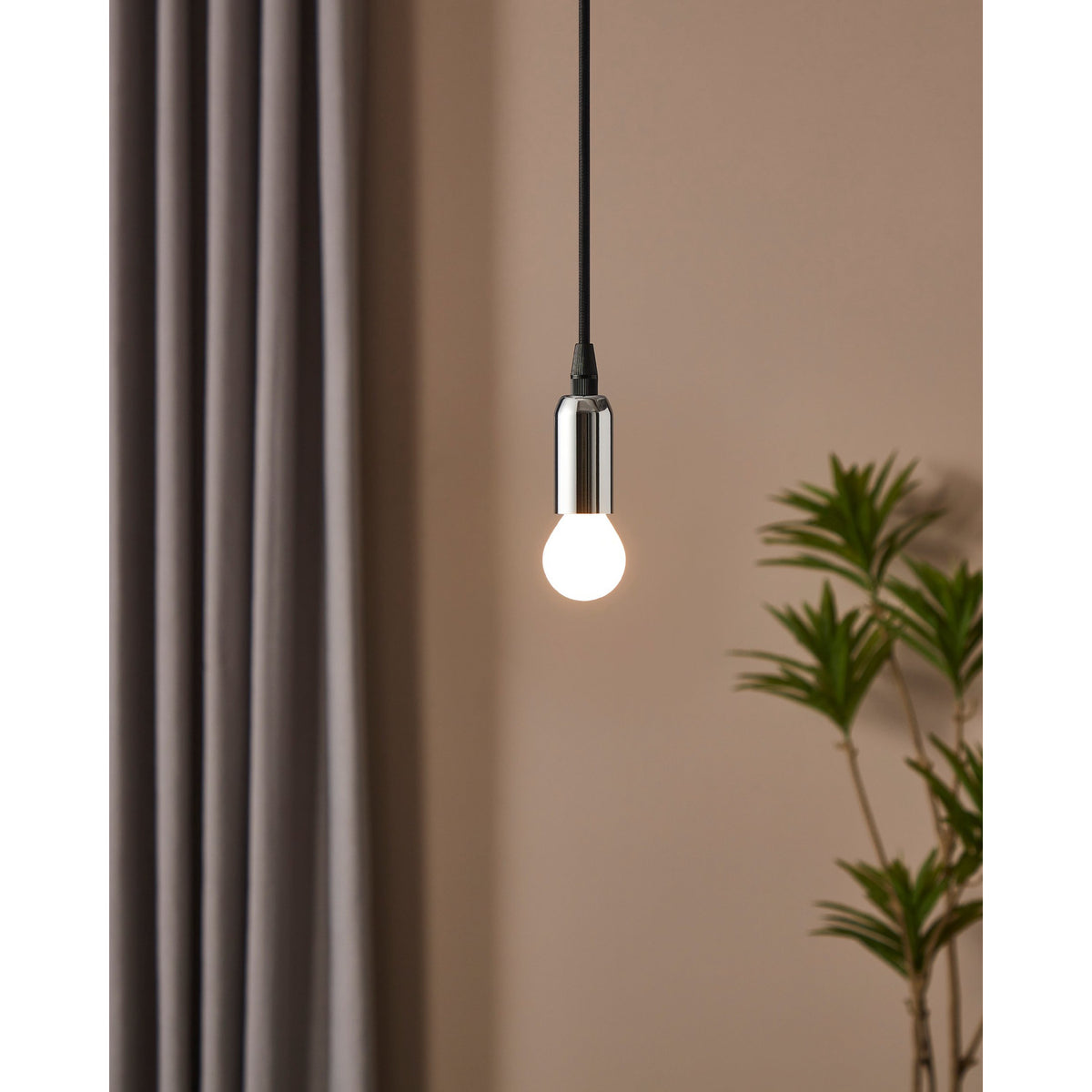 Pendant light with chrome fitting and lit opal LED golf ball bulb, E14 fitting, warm white glow, shown against a beige wall with curtain and plant.