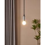 Pendant light with chrome holder and black cable fitted with an Opal Dimmable LED Golf Ball Bulb E14, glowing warm white against a beige wall with curtains and a potted plant.