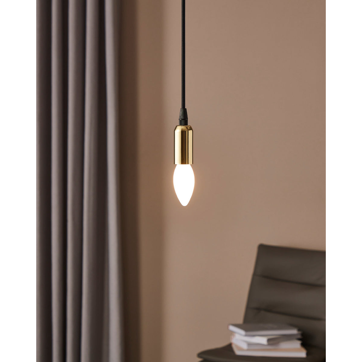 Opal LED candle bulb, E14 fitting, glowing warm white, shown suspended from a black pendant cord with brass holder in a softly lit room.
