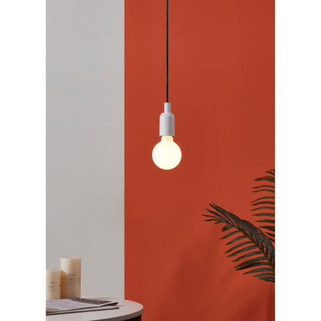 Opal LED globe bulb (E27, G80, warm white) glowing softly in a white pendant fitting against a terracotta wall, with candles and a plant nearby.