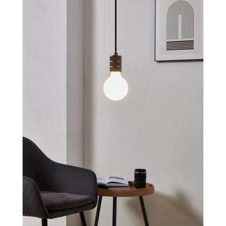 Opal LED Globe Bulb E27 G95 lit warm white in a bronze-finish pendant fitting, shown hanging in a living room beside an armchair and side table.