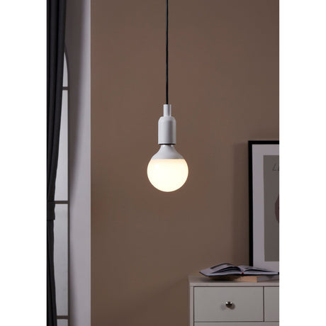 Opal LED globe bulb E27 G95 lit warm white in a white pendant fitting, shown against a brown wall in a room with framed art and a drawer unit.
