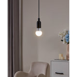 Opal LED GLS bulb, E27 fitting, glowing warm white in a black pendant holder above an armchair, with a cabinet and vase of flowers in the background.