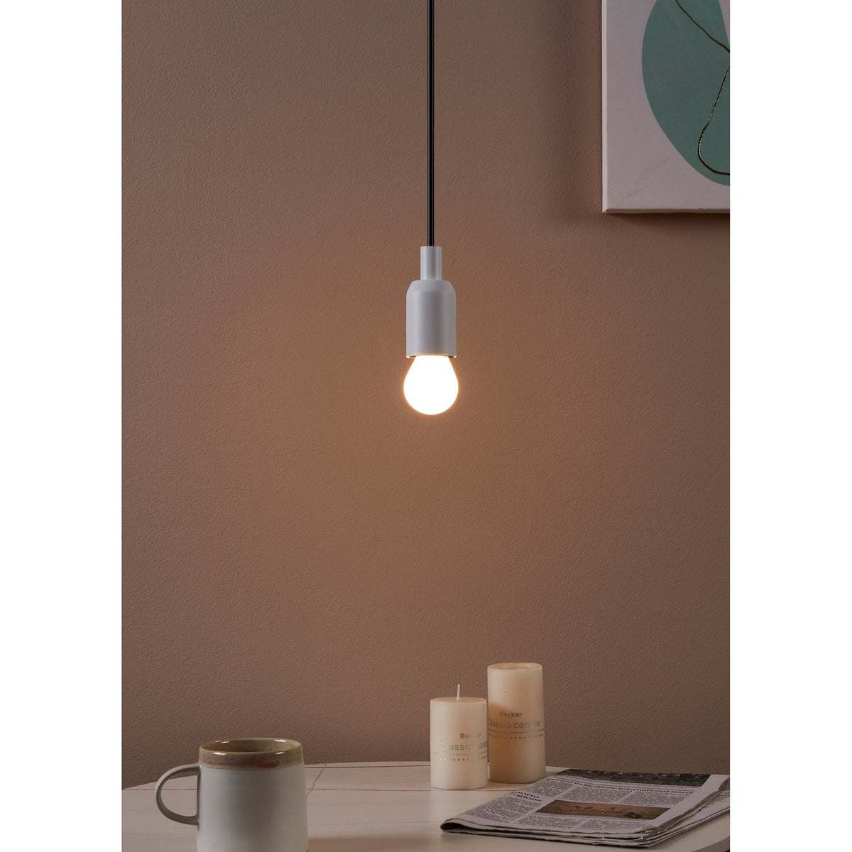 Pendant light with a white cord and holder fitted with an Opal LED Golf Ball Bulb E27, glowing warm white above a desk with candles and a mug.