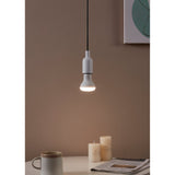 Opal LED reflector bulb E27 R63 lit warm white in a pendant light fitting, shown hanging above a table with candles in a home setting.