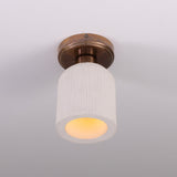 Osier Ceramic Flush Ceiling Light with matt white striped ceramic shade and round brass ceiling plate, lit from below, on a plain white background.