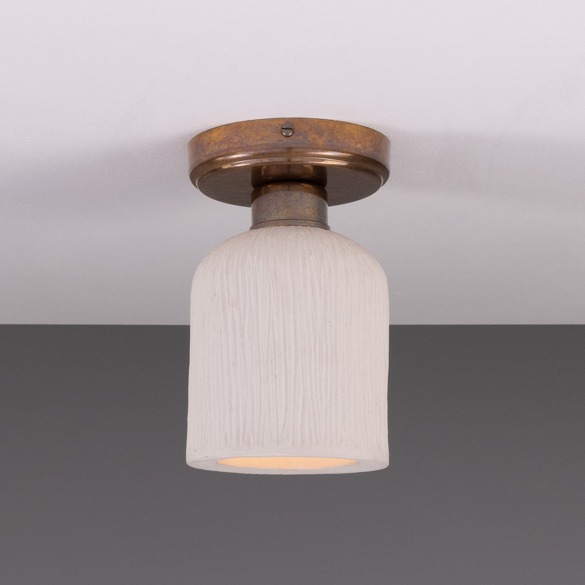 Osier Ceramic Flush Ceiling Light with a matt white striped bell-shaped shade and round brass ceiling plate, shown against a plain grey background.