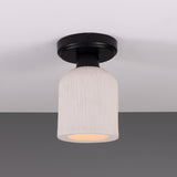 Osier Ceramic Flush Ceiling Light with a matt white striped textured shade and round black ceiling plate, shown glowing against a plain grey background.