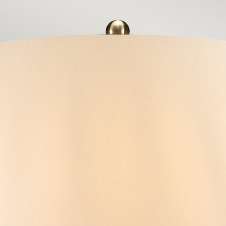 A close-up view showcases the top part of the Ottoman 1 Light Table Lamp - Bronze Metallic/Ivory Shade, complete with a metallic finial. The smooth ivory surface of the shade contrasts with the shiny bronze round metal element adorning its top. The lamp's soft lighting casts a warm and inviting glow.