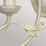 Close-up of the Olivia 2 Light Wall Light, highlighting its ornate ivory and gold patina finish. The design includes a candle holder and delicate leaf embellishments on a gracefully curved stem, showcasing the elegance of handmade lighting craftsmanship.