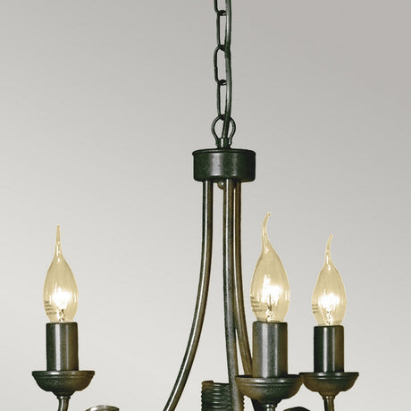 A close-up of the Olivia 3 Light Chandelier - Black/Gold Patina, featuring three unlit candle-shaped bulbs, hangs from a chain against a neutral background. The chandelier showcases elegantly curved arms and a classic black/gold patina design.