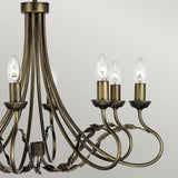 The Olivia 8 Light Chandelier in a black/gold patina showcases gracefully curving arms and eight candle-shaped bulbs. Leaf-like decorations embellish its bronze frame, standing out beautifully against a soft, light gray backdrop.