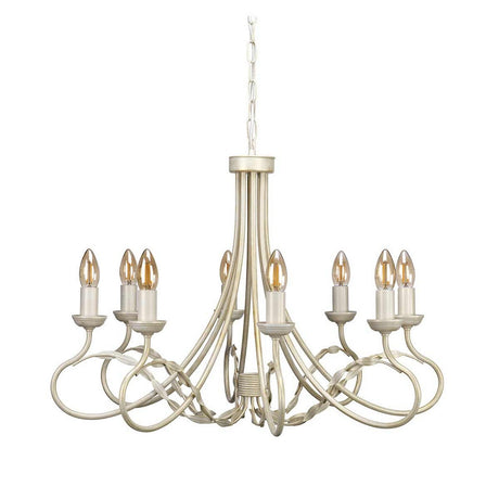 The Olivia 8 Light Chandelier - Ivory/Gold Patina is a traditional handmade chandelier with an ornate design, featuring eight candle-shaped light fixtures. It boasts an ivory finish with a touch of gold patina and intricate curved metal arms, gracefully hanging from a chain.