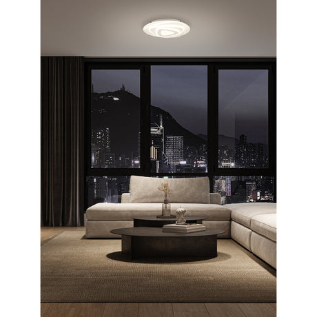 Palagiano LED flush ceiling light in white, round 38cm fixture with layered triangular rings, shown illuminated on a living room ceiling above a night-lit city view.
