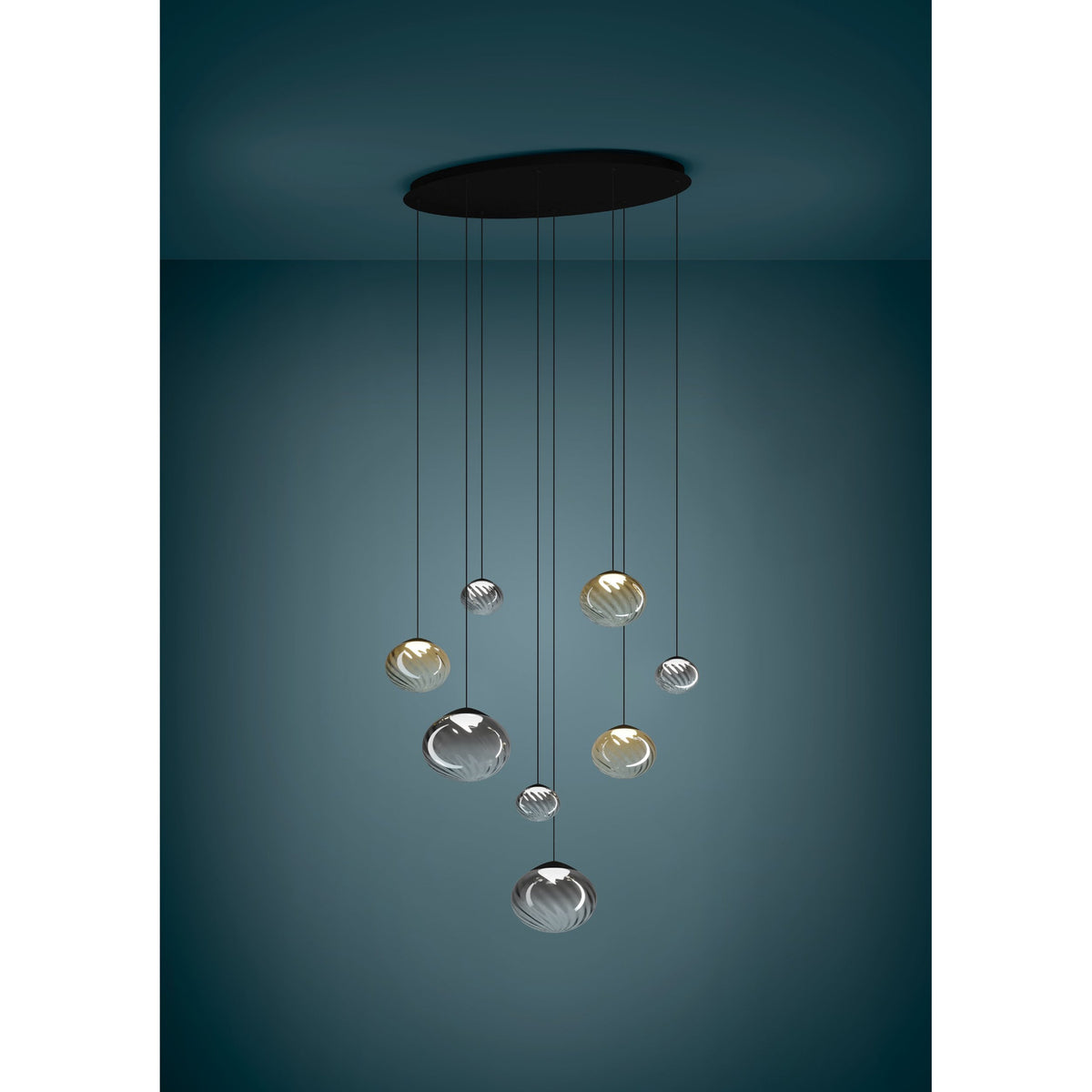Pantoja 8-light cluster pendant with ribbed amber and smoke glass globes at staggered heights, suspended from a black oval ceiling canopy against a dark teal backdrop.