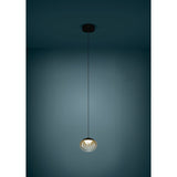 Pantoja pendant light with a round ribbed amber glass globe, black ceiling canopy and black cord, shown illuminated against a dark teal background.