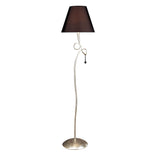 The Paola 1 Light Floor Lamp features a curvy silver stand with decorative loop detail, a black shade, round silver base, and elegant glass droplets hanging below the shade.