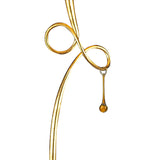 The Paola 1 Light Floor Lamp features a gold, curved abstract metal body with a dangling glass droplet, black shade, and elegant design—isolated on a white background.