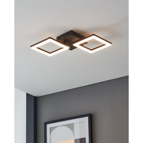 Paranday Smart LED Flush Ceiling Light in black, featuring two diagonal square rings on a compact canopy, shown illuminated on a ceiling above a grey-walled room with framed art below.