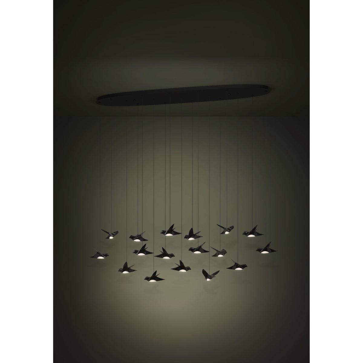 Paratebueno 17 Light Linear Pendant Light in black, bird-shaped shades suspended from an oval ceiling canopy, warm white LED glow in a dimly lit room.