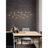 Paratebueno 2 17 Light Linear Pendant Light in brass, bird-shaped shades at varied heights, hung above a dining table in a grey-walled dining room.