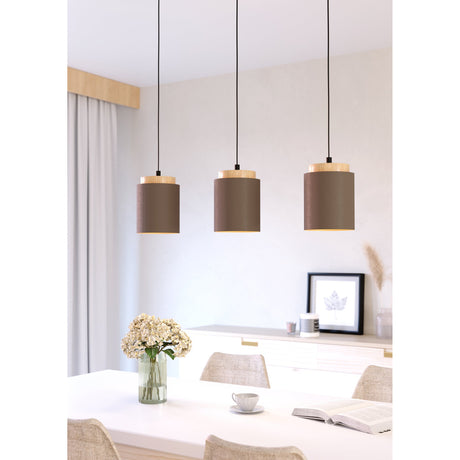 Pavessa three-light linear pendant with cylindrical brown fabric shades, pale wood caps and black cords, shown above a dining table.